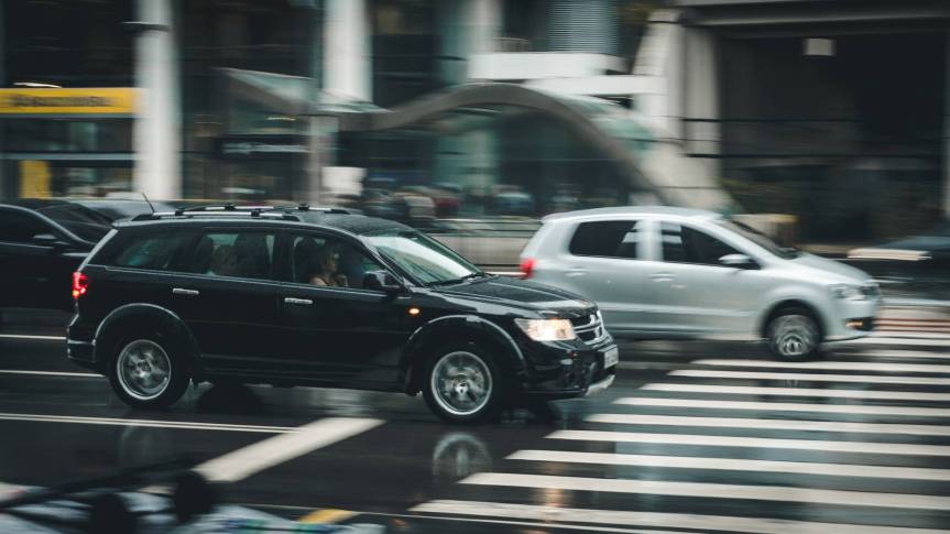 black suv beside grey auv crossing the pedestrian line during daytime